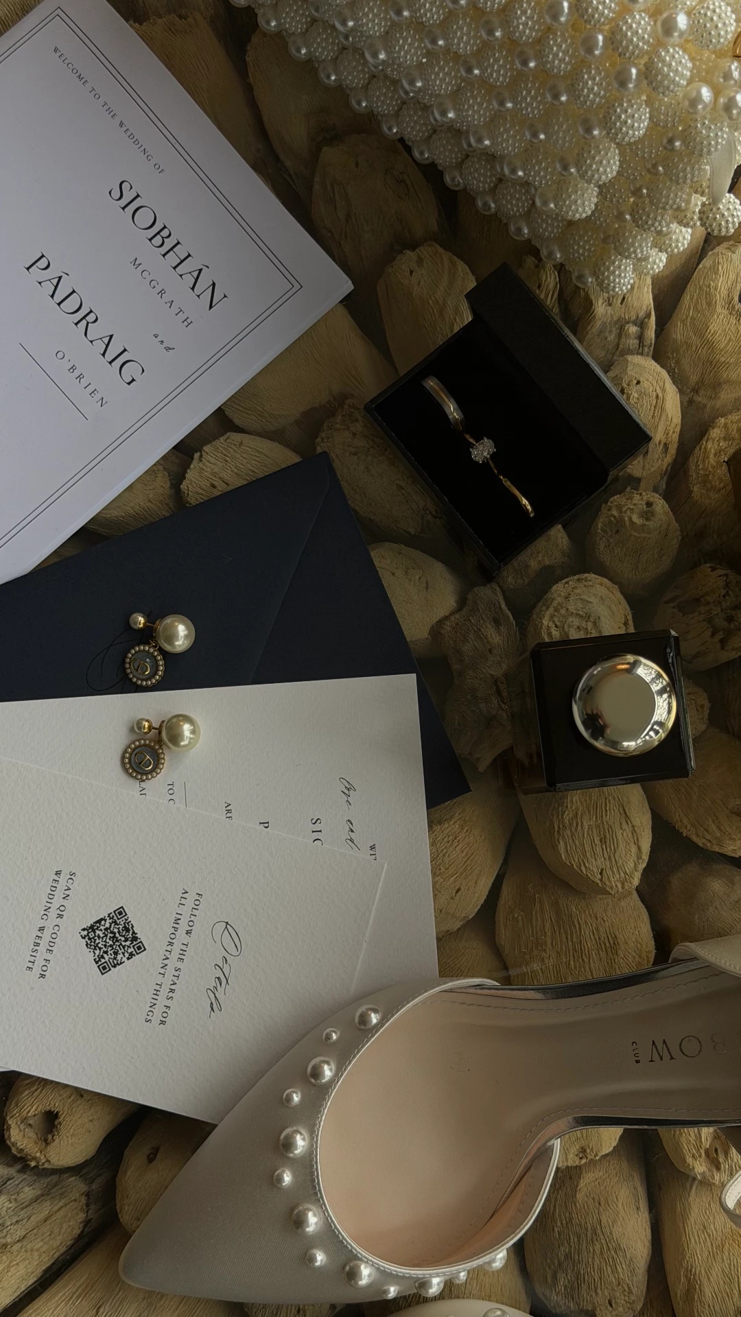 Wedding details flatlay: invitation, rings, pearl earrings and shoes