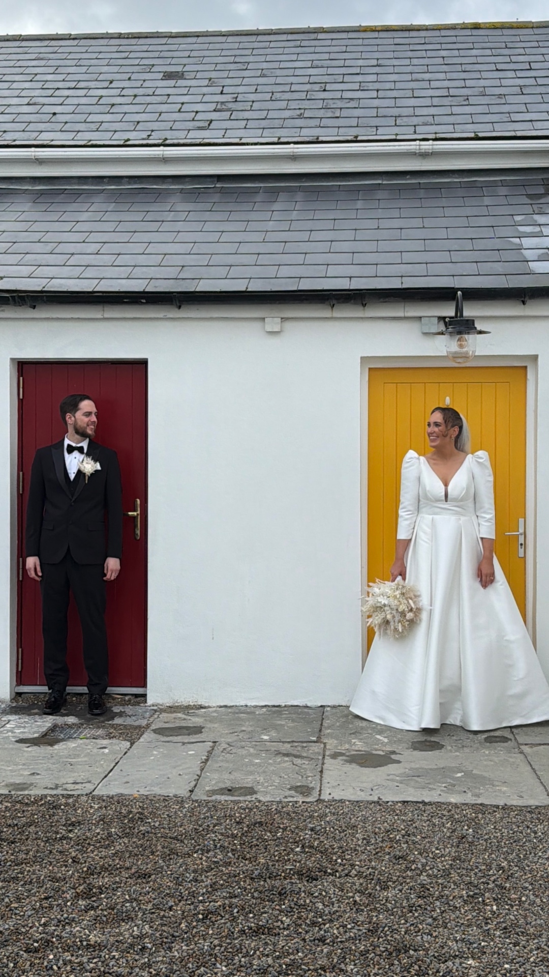 Siobhan and Podge either side of a red and yellow door for a first look