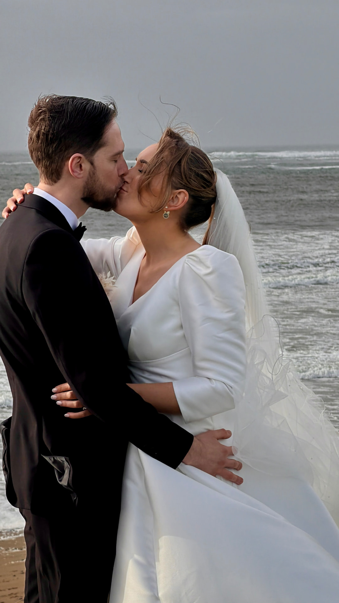 Siobhan and Podge kissing on Spanish Point beach with the Atlantic behind them