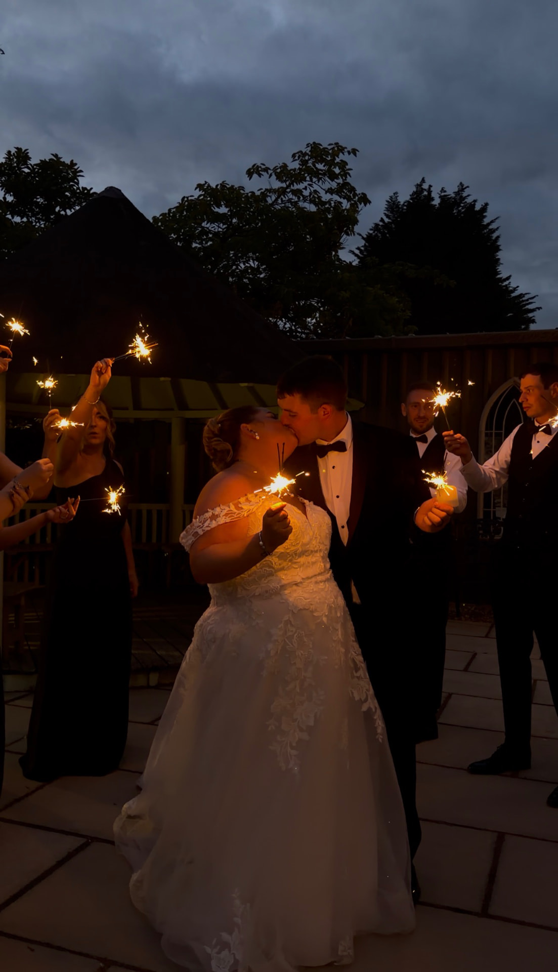 Teaghan and Tony kissing in a sparkler send off at dusk